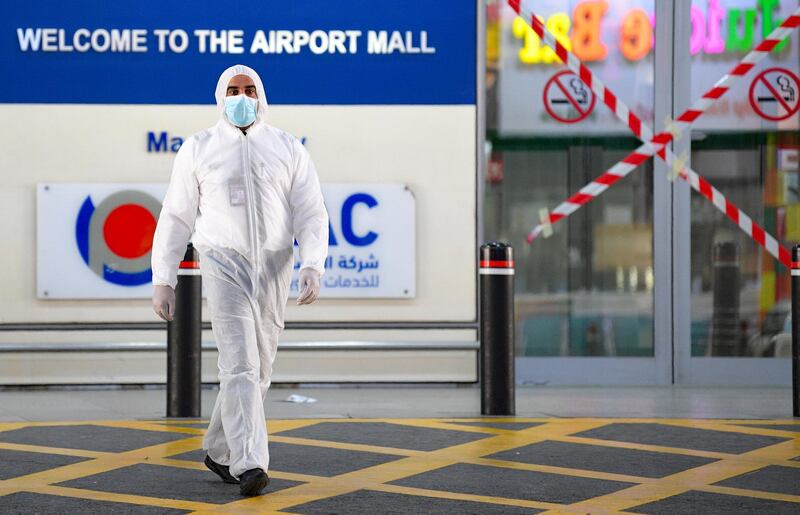 An airport staff member wearing Personal Protective Equipment (PPE) stands at entrance of the Kuwait International Airport, in Kuwait city, Kuwait.  EPA