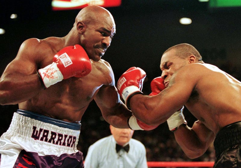 FILE PHOTO: WBA Heavyweight Champion Evander Holyfield (R) connects to the jaw of challenger Mike Tyson in the first round of their title fight June 28.  Evander Holyfied retained his World Boxing Association heavyweight title on Saturday night when Mike Tyson was disqualified for biting Holyfield twice in the third round./File Photo