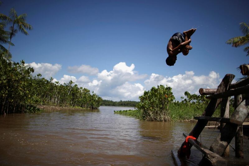 A child jumps in Ilha da Salvacao river, at the riverside community Galileia, as healthcare workers visit riverside communities to check on residents during the coronavirus disease (COVID-19) outbreak, in the municipality of Melgaco, at Marajo island, Para state, Brazil, June 4, 2020. Picture taken June 4, 2020. REUTERS/Ueslei Marcelino