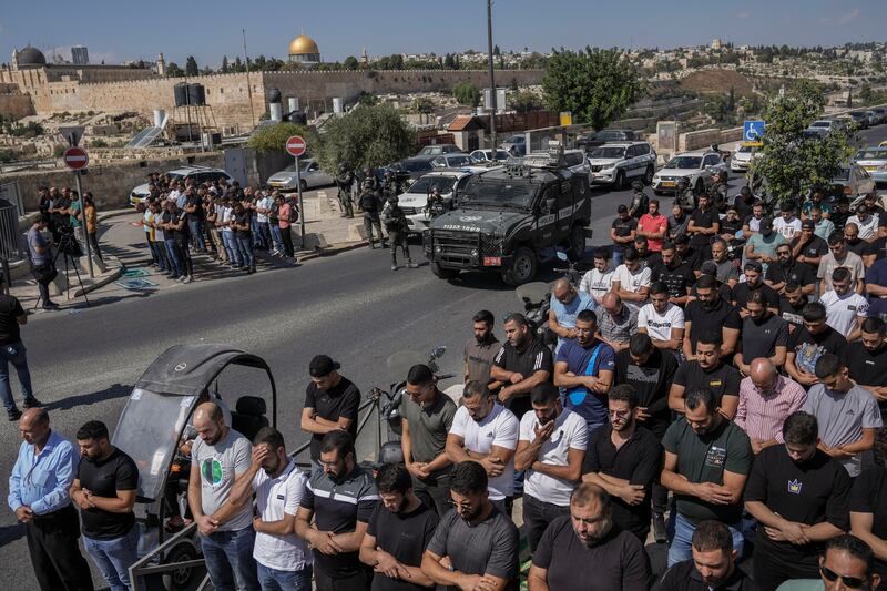 Palestinian worshippers pray outside Jerusalem's Old City while Israeli forces stand guard last October. AP