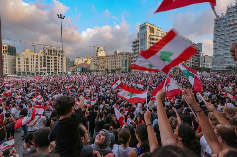 Protesters wave Lebanese flags and chnat anti-government slogans in front the Government palace in Beirut.  EPA