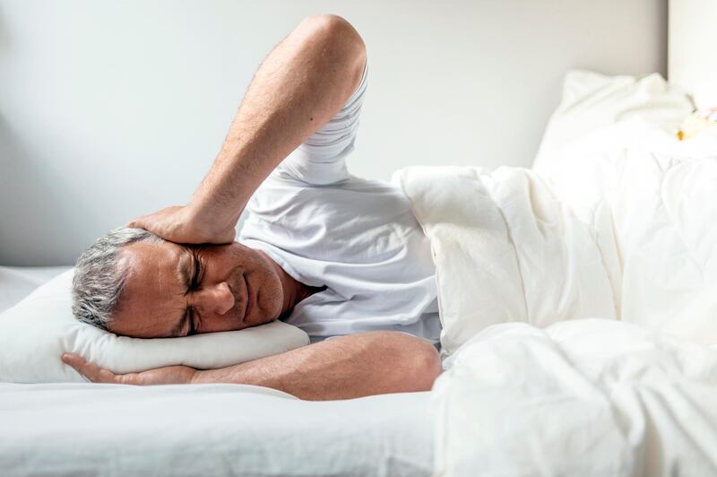 Mature Caucasian man in bed with headache lying in bed during the day. Getty Images