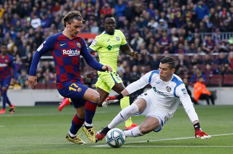 Barcelona's Antoine Griezmann, left, prepares to shoot past Getafe's goalkeeper David Soria to score his side's opening goal during a Spanish La Liga soccer match between Barcelona and Getafe at the Camp Nou stadium in Barcelona, Spain, Saturday Feb. 15, 2020. (AP Photo/G.Garin)