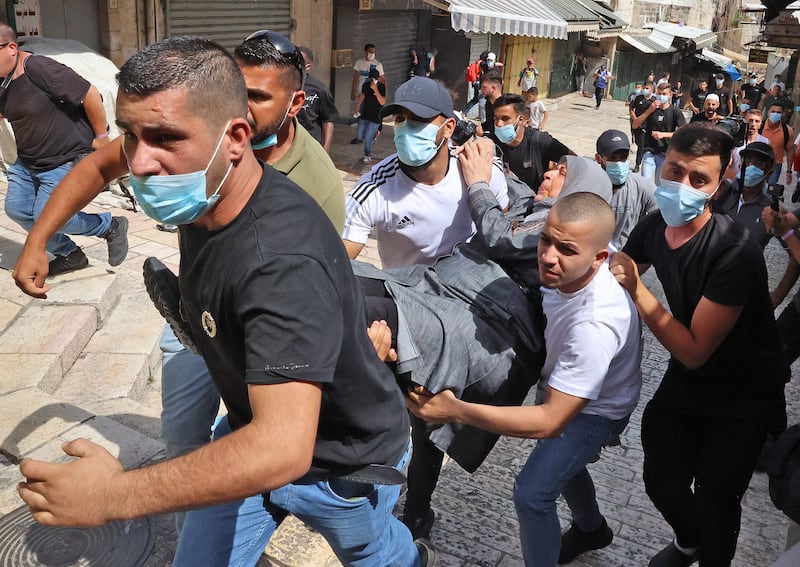 Palestinian protesters carry a woman hit by tear gas as chaos broke out. AFP