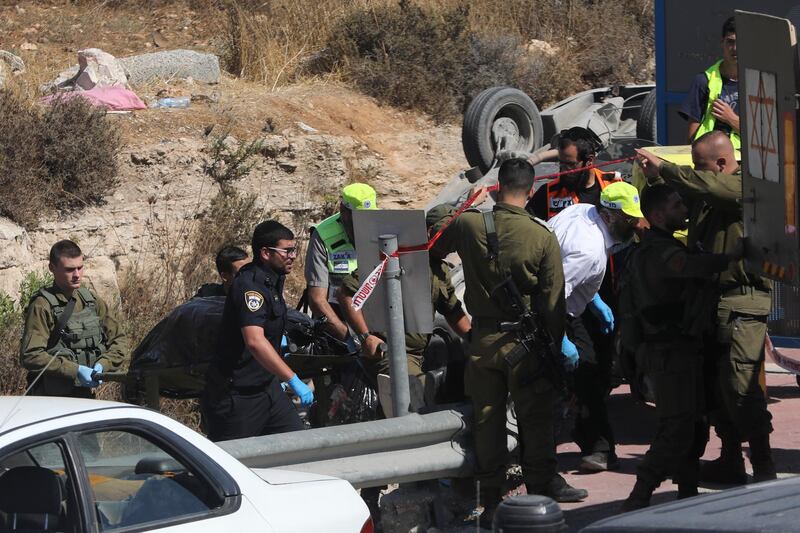Israeli security and emergency services carry the body of a Palestinian driver after a car ramming attack near Gush Etzion settlement cluster in the West Bank, Friday, Aug. 17, 2019. The Israeli military says a Palestinian driver has been shot and killed after he rammed his car and injured two Israelis in the West Bank. (AP Photo/Mahmoud Illean)