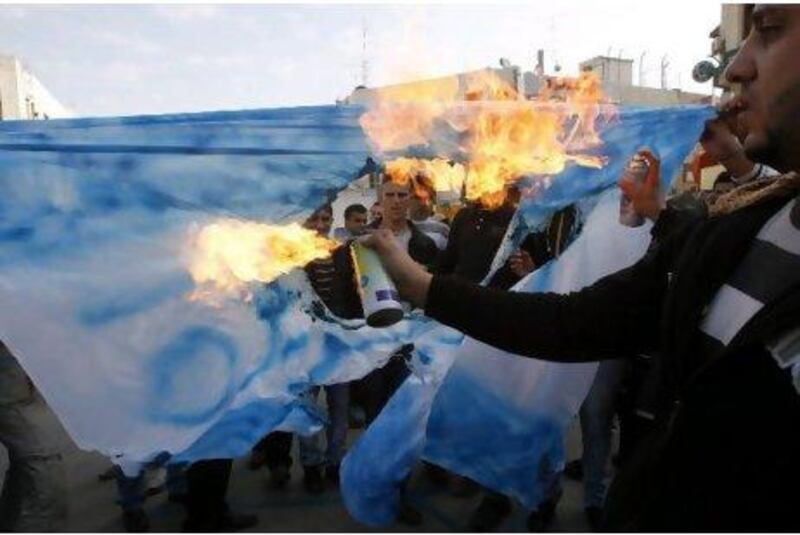 Palestinians burn a mock Israeli flag with anti-Al Jazeera slogans written on it during a protest outside the network's Ramallah office on Monday.