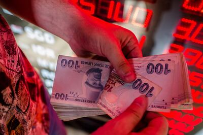 TOPSHOT - A money changer counts Turkish lira banknotes at a currency exchange office in Istanbul, on August 8, 2018. - The Turkish lira on August 1 slumped to record lows of 5,0 against the dollar as the US hit Turkey's justice and interior ministers with sanctions over the case of an American pastor on trial for terror-related charges. (Photo by Yasin AKGUL / AFP)