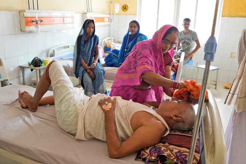 A woman wipes the head of her ailing husband at the hospital in Ballia