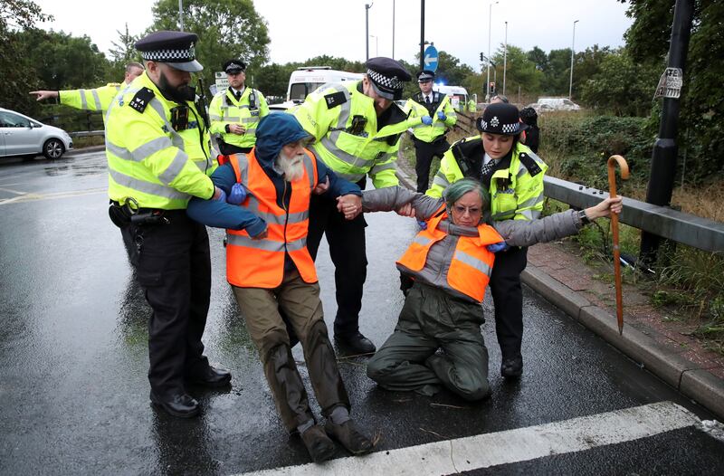 Police officers detain Insulate Britain activists. Reuters