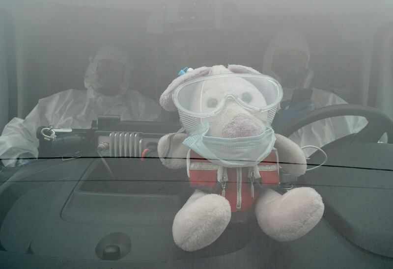 A mascot puppet wearing protective mask and glasses is photographed on the dashboard of a coronavirus ambulance in front of a hospital in Warsaw, Poland on the first day of the new partial lockdown.  AFP