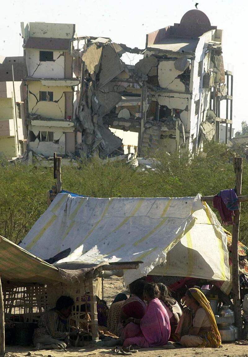 A homeless family takes temporary shelter in a make-shift tent, 27 January 2001, in front of a wrecked building in Bhuj town in Gujarat that was destroyed in an earthquake that struck north western India 26 January rendering thousands homeless. At least 3000 people are feared dead as a result of the tremor, with casualties expected to rise. AFP PHOTO/Arko DATTA (Photo by ARKO DATTA / AFP)