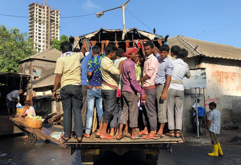 Indian workers travel on the back of a lorry in Mumbai. Punit Paranjpe / AFP