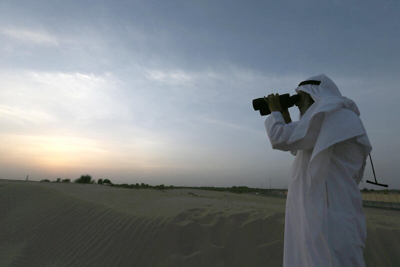 DUBAI , UNITED ARAB EMIRATES – July 9 : Hasan Al Hariri , an astronomer watching the Ramadan moon from his binocular near Mushrif park in Dubai. ( Pawan Singh / The National ) For News.  Story by Nadeem Hanif