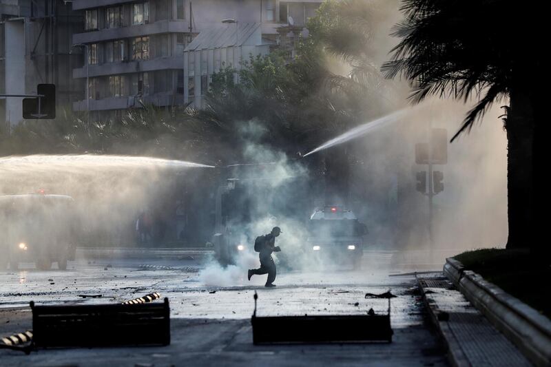 A demonstrator runs past police water cannons in Santiago, Chile. Reuters