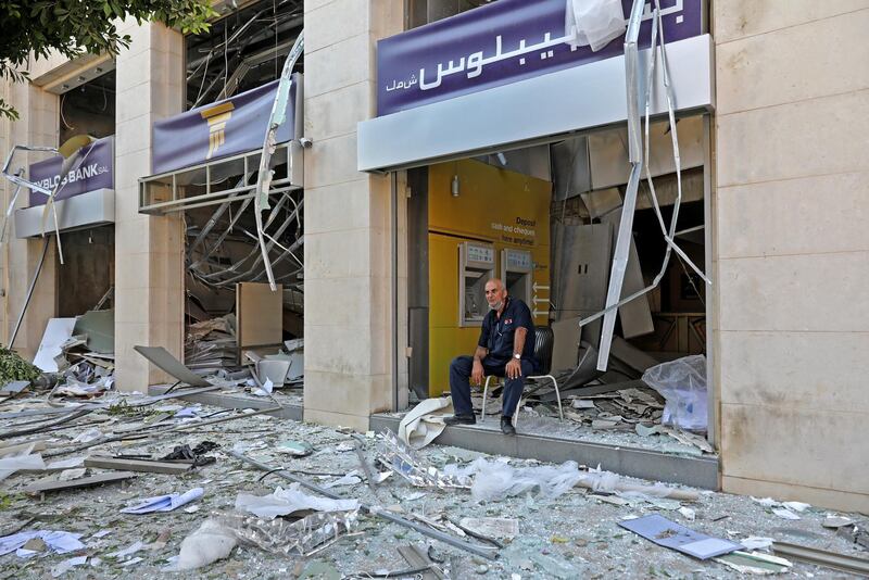 A man sits at the entrance of a damaged bank in the aftermath of yesterday's blast that tore through Lebanon's capital and resulted from the ignition of a huge depot of ammonium nitrate at Beirut's port, on August 5, 2020. - Rescuers searched for survivors in Beirut after a cataclysmic explosion at the port sowed devastation across entire neighbourhoods, killing more than 100 people, wounding thousands and plunging Lebanon deeper into crisis. (Photo by ANWAR AMRO / AFP)