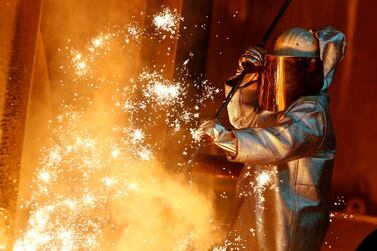 A steel worker stands amid sparks of raw iron coming from a blast furnace at a ThyssenKrupp steel factory in Duisburg, western Germany. Reuters