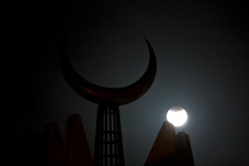 The partially-eclipsed moon rises against a crescent mounted on Faisal Mosque in Islamabad, Pakistan. B.K. Bangash / AP Photo.