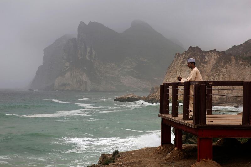 A man watches waves crashing on to the rocky coastline at Salalah.