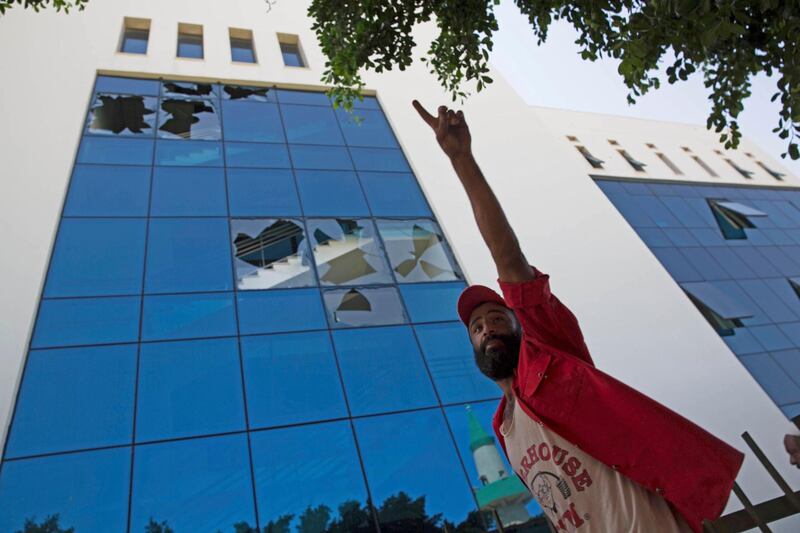 A man stands outside the damaged headquarters of the national oil company. AP Photo