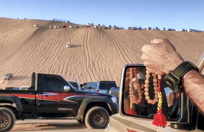 Abu Dhabi, United Arab Emirates, January 2, 2020.  A desert 4x4 enthusiast enjoys the view of the peek of the  the Mureeb Dune while holding his prayer beads at the LIWA International Festival 2020.
Victor Besa / The National
Section:  NA
Reporter:  Haneen Dajani