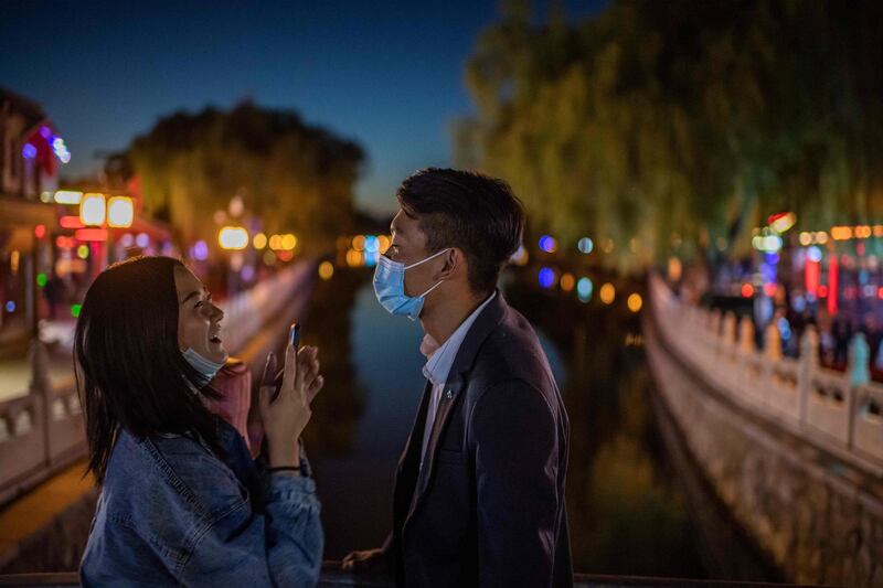 A couple share a laugh as they take pictures with a phone on a bridge at the Hu Hai lake in Beijing, China. AFP