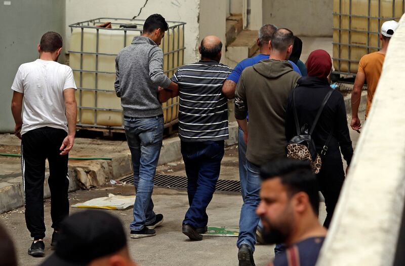 A grieving man is helped away at the entrance of the morgue of a hospital in Tripoli. AFP