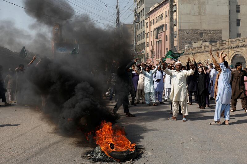 Supporters of the Tehrik-e-Labaik Pakistan Islamist political party chant slogans as they set ablaze tires to block the road. Reuters
