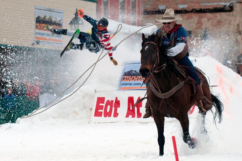 Jeff Dahl races down Harrison Avenue while skier Vincent Pestello looses control of the first jump of the Leadville ski joring course during the 71st annual Leadville Ski Joring weekend competition in Leadville, Colorado. AFP