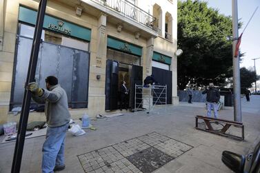 Workers fix iron shields on the windows of shops to protect them from damage during anti-government riots in the Lebanese capital Beirut's downtown district, on January 24, 2020. / AFP / JOSEPH EID