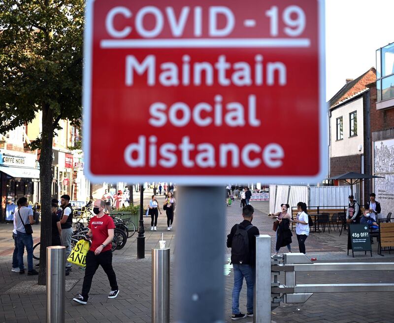 People walk past a sign encouraging social distance in a shopping street in Solihull, central England. AFP