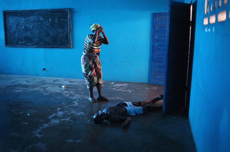 Umu Fambulle stands over her husband Ibrahim after he staggered and fell, knocking him unconscious in an Ebola ward on August 15 in Monrovia, Liberia. People suspected of contracting the Ebola virus are being sent by Liberian health workers to the centre, a closed primary school originally built by USAID.  John Moore / Getty Images