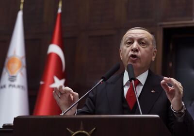 Turkish President Recep Tayyip Erdogan addresses his ruling party members at the parliament, in Ankara, Turkey, Wednesday, Feb. 12, 2020. Erdogan said Wednesday that Turkey will attack government forces anywhere in Syria if another Turkish soldier is injured. (AP Photo/Burhan Ozbilici)