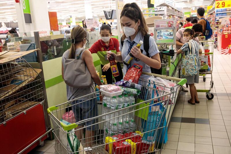 A woman wearing a face mask takes goods out of her cart as she shops at a supermarket in Bangkok, Thailand. Jack Taylor / AFP