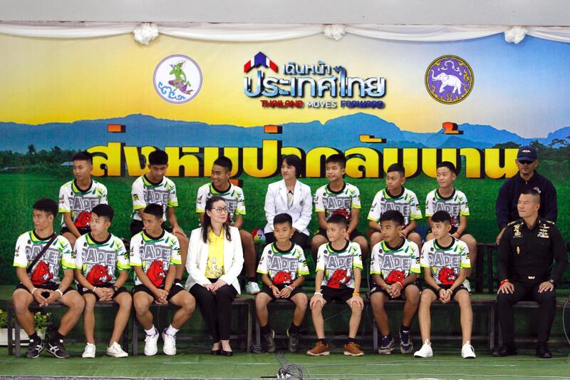 epa06896312 Twelve rescued members of the Wild Boar soccer team and their assistant coach sit with Thai health officers and soldiers to make their first public appearance during a military governmental TV pool broadcasting program at Chiang Rai Provincial Administrative Organization in Chiang Rai province, Thailand, 18 July 2018. The thirteen members of Wild Boar child soccer team, including their assistant coach, who were trapped in the Tham Luang cave since 23 June 2018, made their first appearance on the day for a tightly-controlled interview with the media after they were rescued, before returning to their homes with families.  EPA/PONGMANAT TASIRI