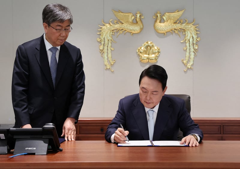 Mr Yoon signs a document as he works at the new Presidential Office in Seoul. Reuters
