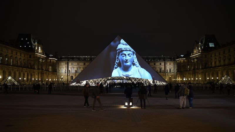 Images of the art displayed in the Louvre Abu Dhabi are projected onto the Louvre Pyramid in Paris Wednesday night to mark the opening of the museum on Saadiyat island. Eric Feferberg / AFP