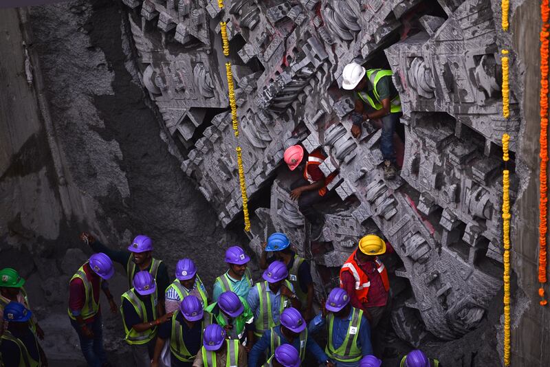 Construction workers come out through a tunnel boring machine after it broke the wall to complete digging on a metro rail project in Chennai, India. EPA