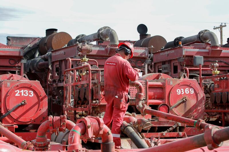 FILE - In a Monday, June 26, 2017, file photo, a Halliburton employee works near rows of hydraulic fracturing pumping units at a three pad site in Midland, Texas. Halliburton Co. reports earnings, Monday, Jan. 22, 2018. (Steve Gonzales//Houston Chronicle via AP, File)