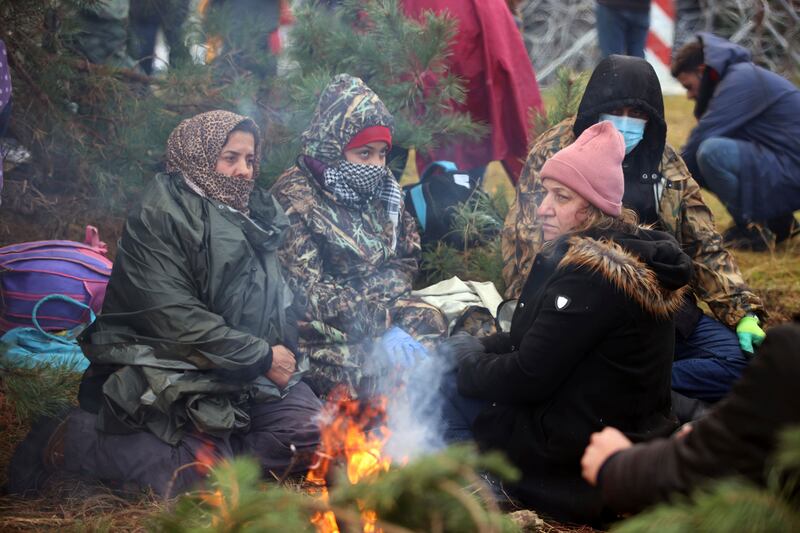 People keep themselves warm with a fire. AP