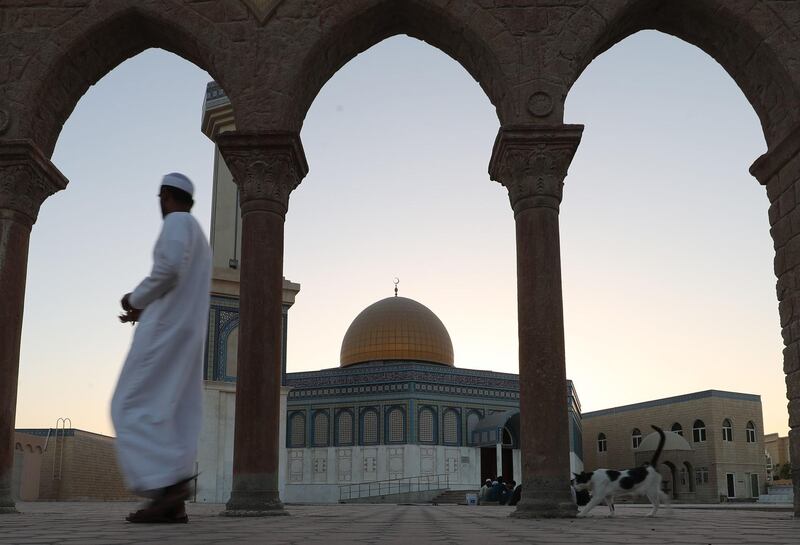 A cat follows a man in front of the Bani Hashim Mosque, Abu Dhabi, in 2018. AFP