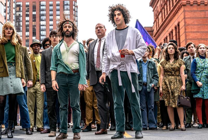 This image released by Netflix shows, foreground from left, Caitlin Fitzgerald, Jeremy Strong and Sasha Baron Cohen in a scene from "The Trial of the Chicago 7."  (Nico Tavernise/Netflix via AP)