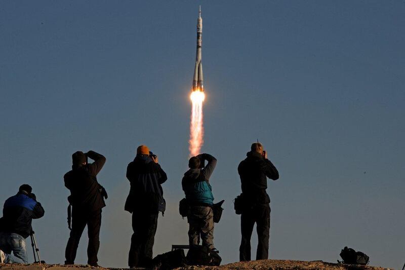 Onlookers take photographs as Russia’s Soyuz TMA-11M spacecraft carrying an unlit Olympic torch and an international crew including Japanese astronaut Koichi Wakata, Russian cosmonaut Mikhail Tyurin and US astronaut Rick Mastracchio blasts off from the Russian leased Kazakh Baikonur cosmodrome this morning. Kirill Kudryavtsev / AFP Photo