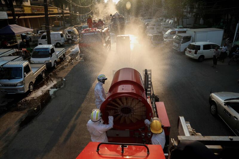 Firefighters wearing protective clothing spray disinfectant along a street as a preventive measure against the spread of the coronavirus in Yangon. AFP