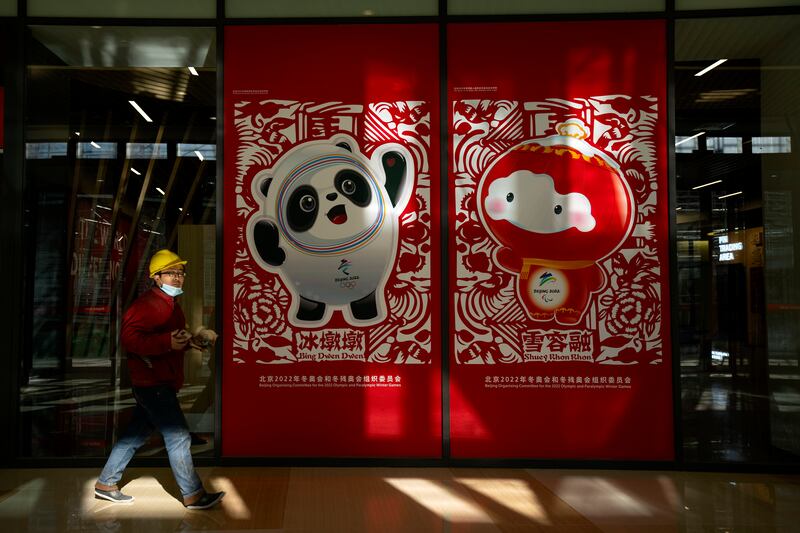 A worker walks past posters showing the Olympic mascot Bing Dwen Dwen and Paralympic mascot Shuey Rhon Rhon at the Winter Olympic Village in Beijing. AP