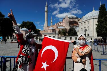 Women holding the Turkish flag gesture outside the Hagia Sophia after a top court overturned its status as a museum on July 10, 2020. Reuters