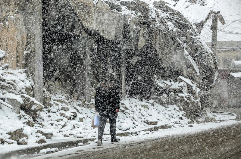 A man walks through a snow blizzard past heavily damaged buildings in Mosul, northern Iraq.  AFP