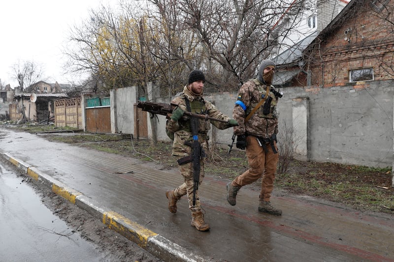 Soldiers carry a Russian machine gun in Bucha. EPA