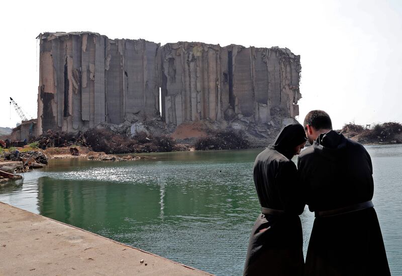 Priests pray near the remains of Beirut port on the first anniversary of the blast that ravaged the port and the city.