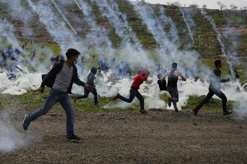 Palestinian demonstrators run away from tear gas fired by Israeli troops during a protest against Jewish settlements, in al-Mughayyir village near Ramallah, in the Israeli-occupied West Bank.   AFP