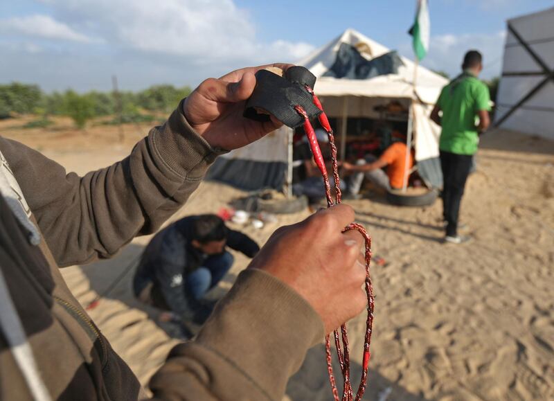 A man prepares a slingshot as Palestinians prepare to demonstrate along the border with the Gaza strip, east of Jabalia. Mohammed Abed / AFP